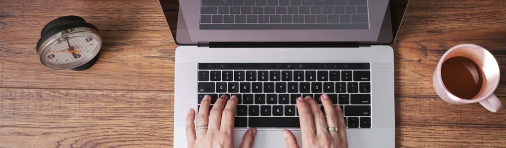 Woman's hands working on laptop at home office, top view
