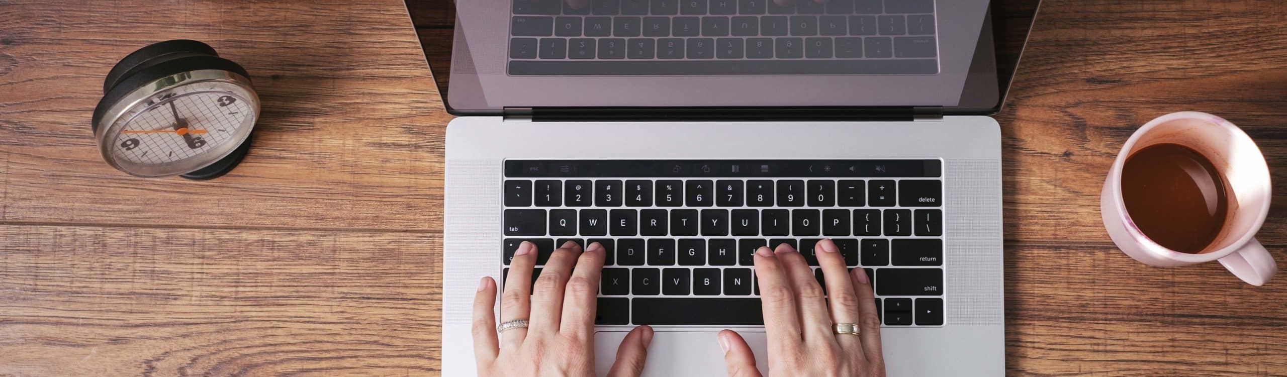Woman's hands working on laptop at home office, top view