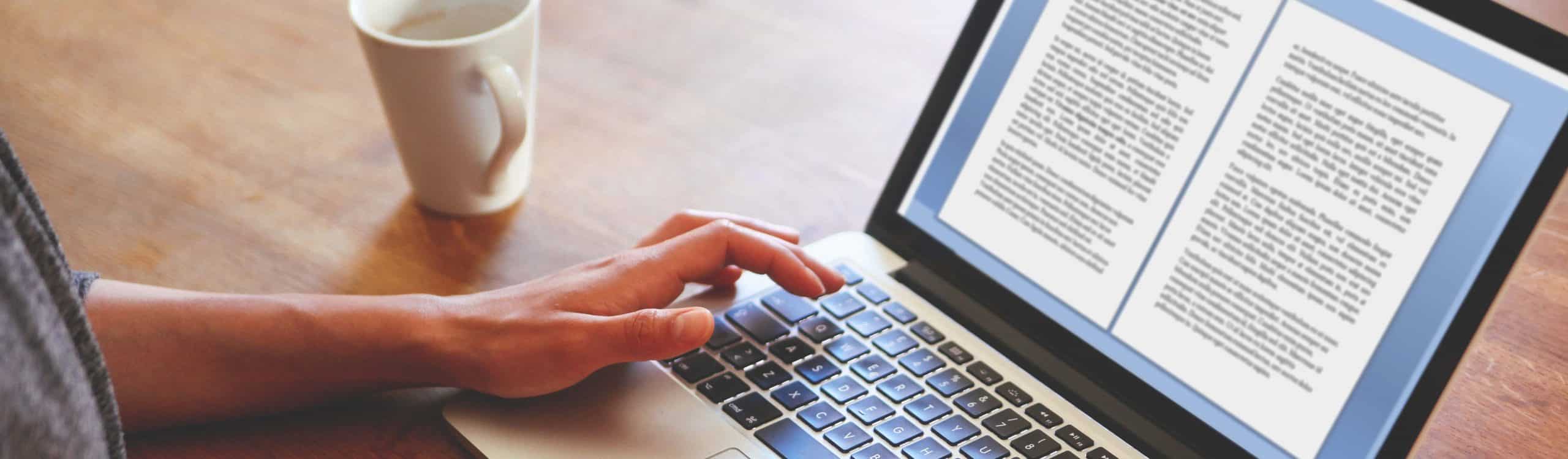 High angle image of a female novelist or blogger, typing on the laptop keyboard while having a cup of coffee. Retro processed with vibrant colors.