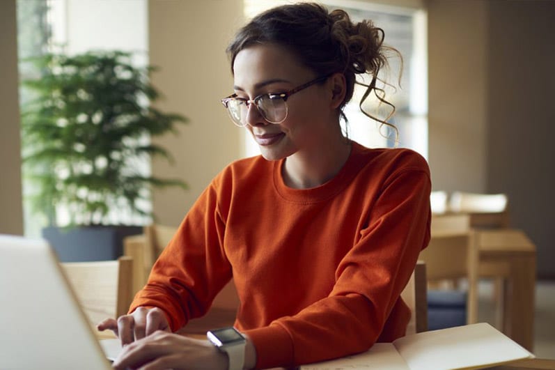 Woman wearing red sweater working on laptop