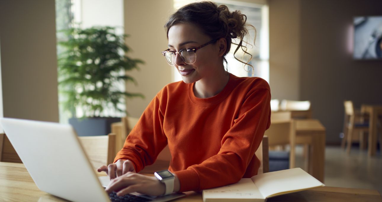 Woman wearing red sweater working on laptop
