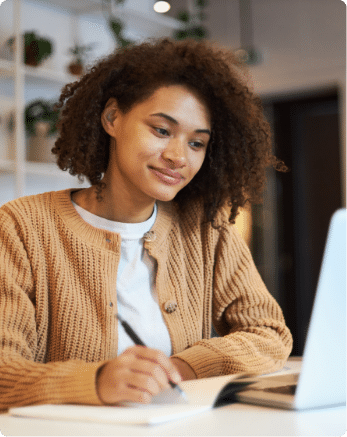 Woman in tan sweater writing in a notepad